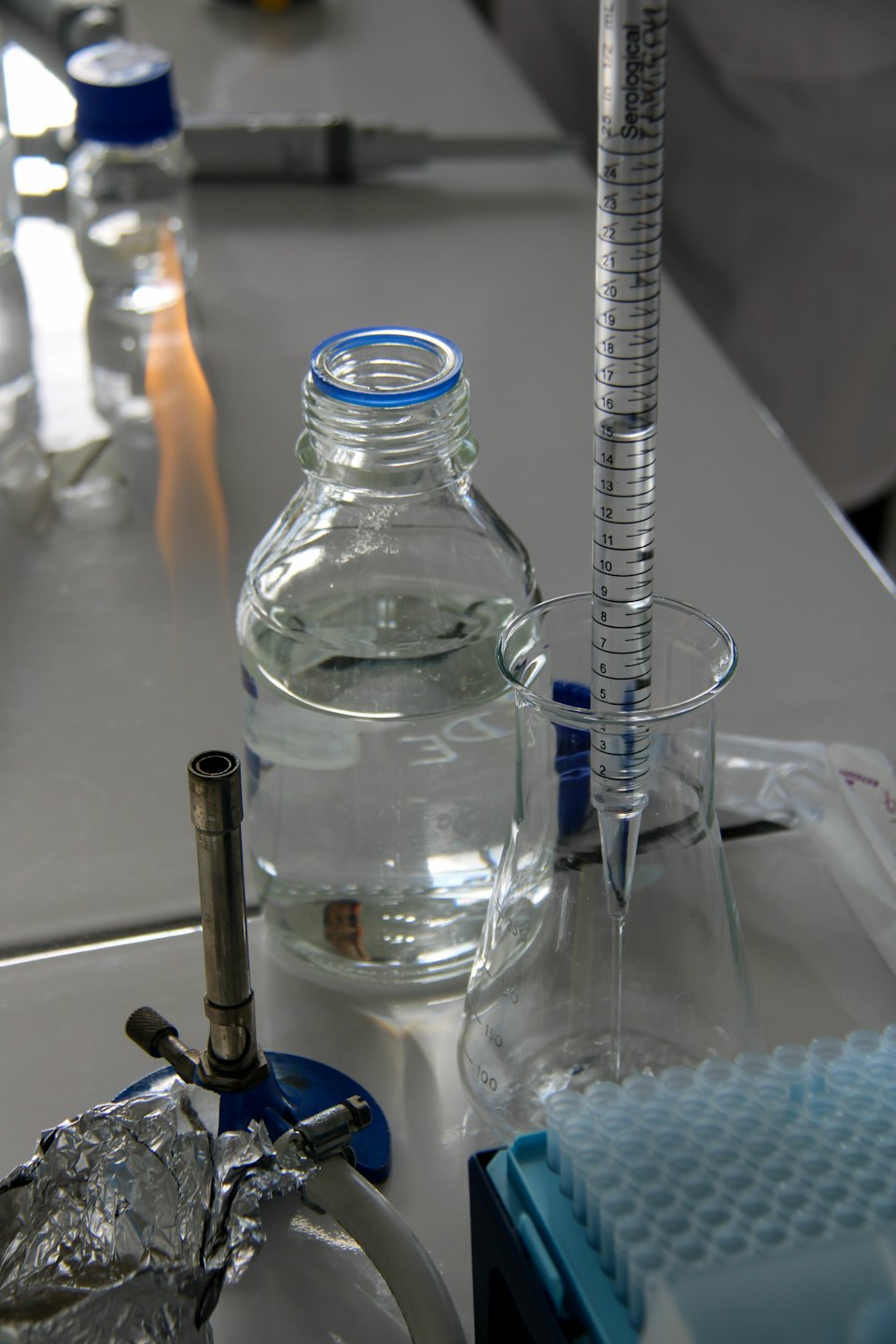 Laboratory equipment with Bunsen burner flame and serological pipette.